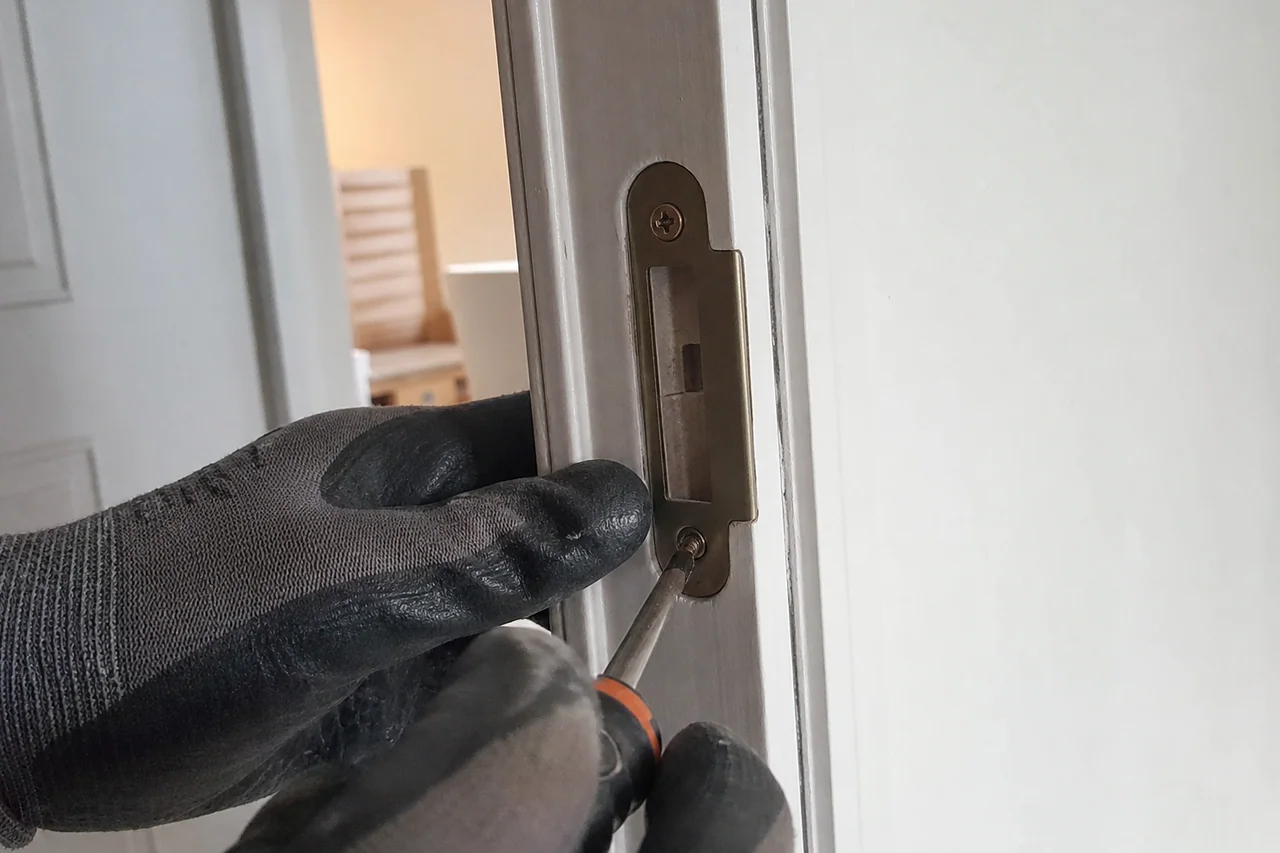 mains règlant la gâche d'une porte